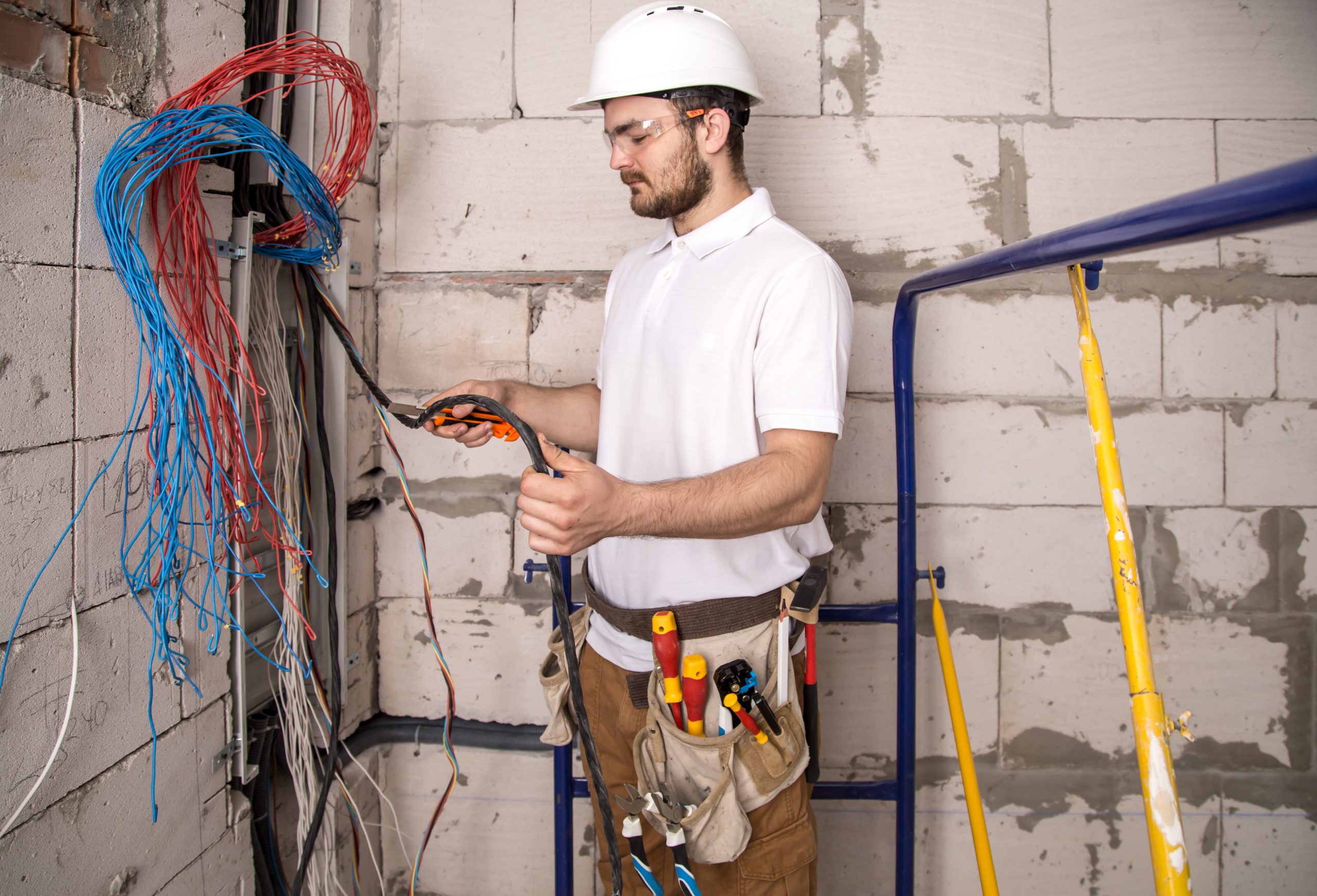 Electrician working near the Board with wires. Installation and connection of electrics. Electrician working near the Board with wires. Installation and connection of electrics. Professional with tools in hand.